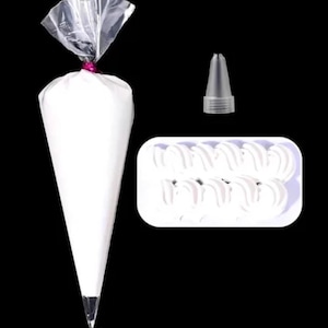 Puede incluir: Una manga pastelera blanca llena de glaseado blanco, una boquilla de metal y una bandeja de espirales de glaseado. La bolsa está sellada con una corbata rosa. Los elementos están sobre un fondo negro.