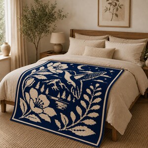 May include: A rectangular woven throw blanket featuring a dark blue background with a cream-colored pattern. The design depicts a hummingbird in flight, large flowers, foliage, a mountain range, a crescent moon, and stars in a grid-like texture.