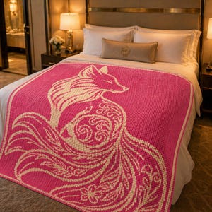 May include: A pink knitted blanket with a cream-colored fox design. The fox is depicted with intricate details, including its fur and tail. The blanket is on a bed with white sheets and pillows.