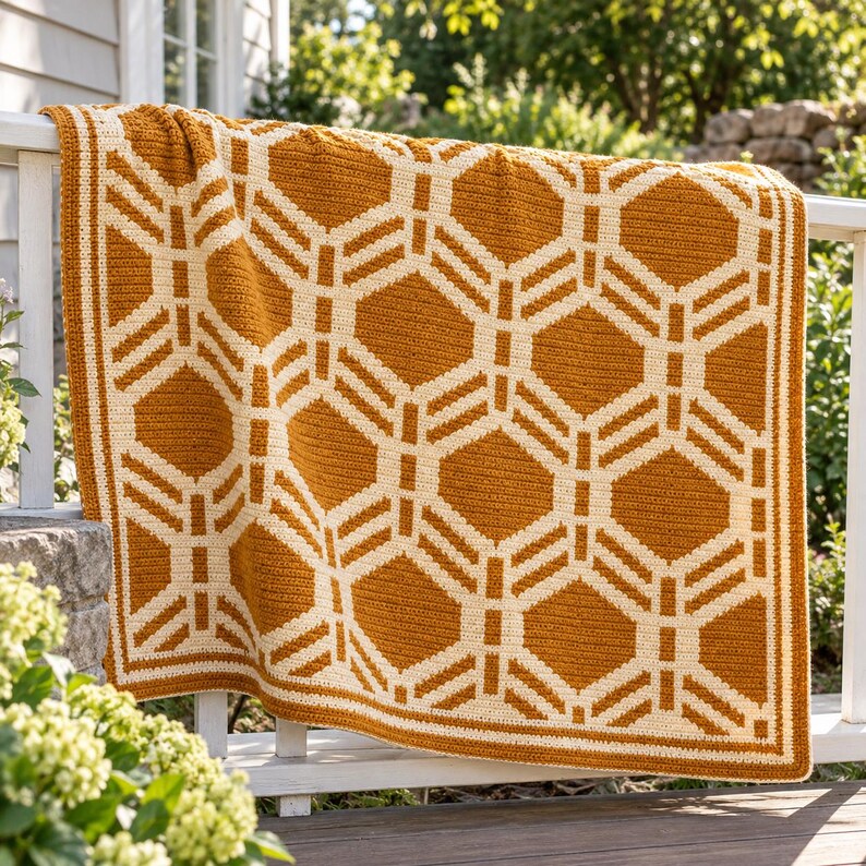 May include: A rectangular crochet blanket featuring a repeating geometric pattern in mustard yellow and cream white. The design consists of interconnected hexagonal shapes with a thick, solid border in the same two-tone color scheme.