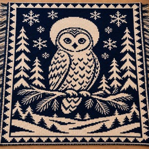 May include: A rectangular woven throw blanket featuring a dark navy blue and cream color scheme. The design displays a central owl perched on a pine branch, surrounded by pine trees and snowflakes, finished with a fringed edge on all sides.