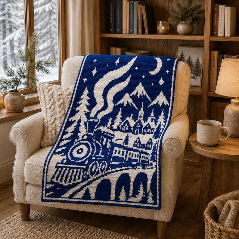 May include: A rectangular crochet blanket featuring a dark blue and white pixelated winter scene. The design depicts a steam train traveling across a bridge toward a village with mountains, pine trees, stars, and a crescent moon in the sky.