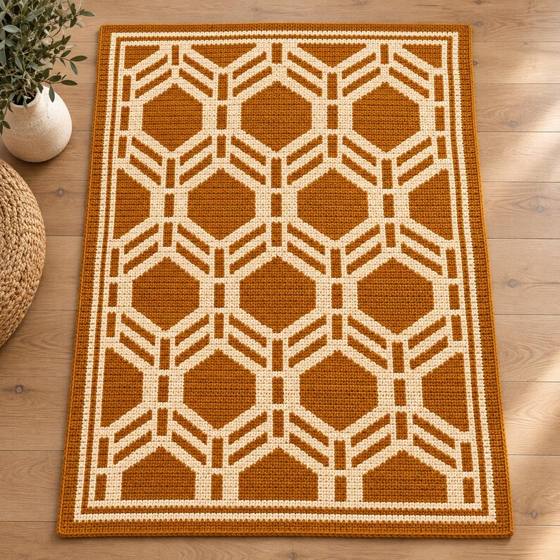 May include: A rectangular area rug featuring a repeating geometric pattern of cream-colored hexagons and lines set against a solid burnt orange background, enclosed by a thick cream-colored border within the orange edge of the rug.