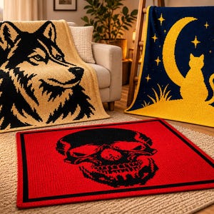 May include: Three rectangular textile items: a beige blanket with a black wolf head graphic, a dark blue blanket with a yellow crescent moon, stars, and a cat silhouette, and a red rug featuring a large black skull graphic with a black border.