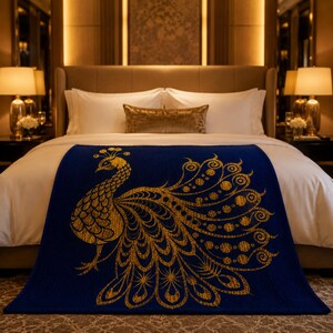 May include: A navy blue bed runner featuring a gold peacock design. The peacock is depicted with intricate detailing, including a fanned tail and a crown. The bed runner is placed on a white bed with a gold pillow.