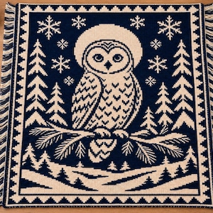 May include: A rectangular woven throw blanket featuring a dark navy blue and cream color scheme. The design displays a central owl perched on a pine branch, surrounded by stylized pine trees, falling snowflakes, and a decorative border with fringe.