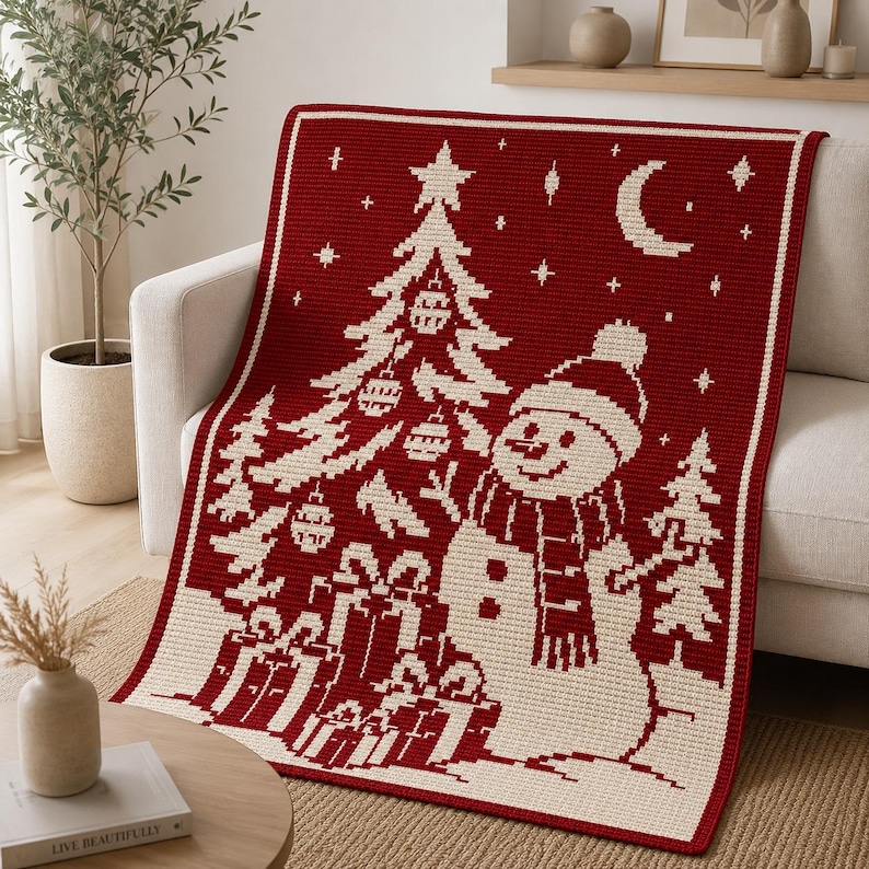 May include: A rectangular crochet blanket featuring a deep red background with a cream-colored pattern. The design displays a decorated Christmas tree, a snowman wearing a hat and scarf, wrapped gift boxes, and a crescent moon with stars.
