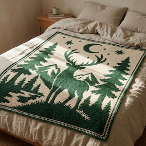 Peut inclure: Une couverture en crochet rectangulaire pr&eacute;sentant une sc&egrave;ne de for&ecirc;t avec un grand cerf au centre. Le motif comprend des sapins vert fonc&eacute;, des montagnes, un croissant de lune et des &eacute;toiles sur un fond cr&egrave;me avec une bordure.