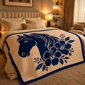 May include: A beige crochet throw blanket with a navy blue horse head and floral design. The blanket has a navy blue border and is displayed on a bed. The throw blanket is a decorative home textile.