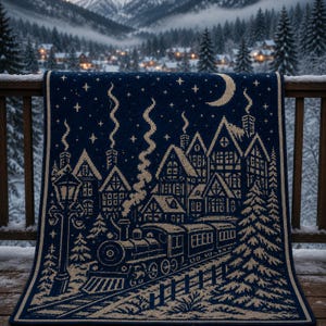 May include: A dark blue and cream knit blanket featuring a detailed winter scene with a steam locomotive, a row of houses with smoking chimneys, a tall street lamp, pine trees, a crescent moon, and a starry night sky pattern.