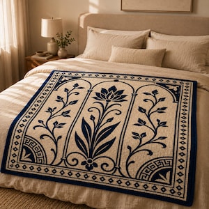 May include: A rectangular beige throw blanket with a navy blue floral design and border. The design features a central lotus flower and stylized leaves within arched panels. The border has geometric patterns.