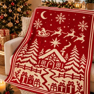 May include: A rectangular knit throw blanket featuring a deep red background with cream-coloured patterns. The design depicts a winter scene with a cabin, pine trees, a fence, wrapped gifts, a crescent moon, snowflakes, and a sleigh with reindeer.