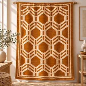 May include: A rectangular crochet wall hanging featuring a geometric pattern of interlocking hexagons in burnt orange and cream yarn. The textile is suspended from a wooden rod and displays a repeating symmetrical design with a thick border.