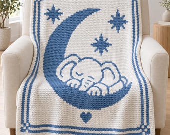 May include: A cream-colored crochet blanket featuring a blue design of a sleeping elephant resting on a crescent moon. The pattern includes three blue stars and a small blue heart at the bottom, all framed by a blue rectangular border.