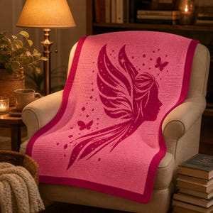 May include: A pink crocheted blanket draped over a chair. The blanket features a dark pink fairy silhouette with butterfly accents. The blanket has a dark pink border and is made of soft material. The blanket is a cozy home decor item.