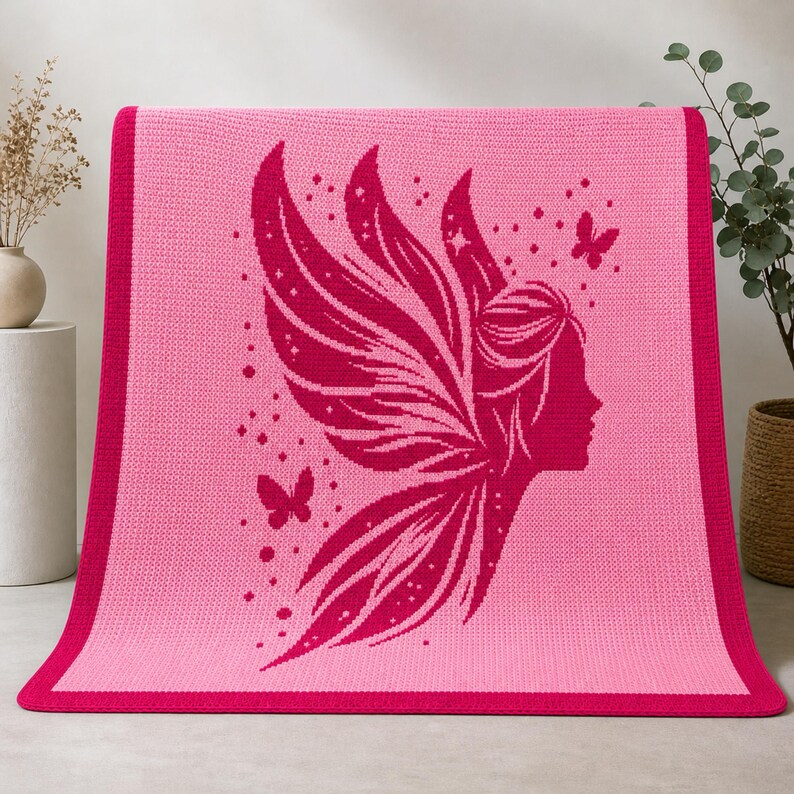 May include: A pink knitted blanket featuring a magenta fairy silhouette with large wings, butterflies, and stars. The blanket has a solid pink center with a magenta border. The design is a whimsical and decorative element.