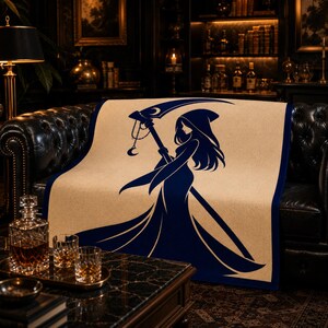 May include: A rectangular throw blanket featuring a beige background with a dark blue border and a large, central graphic of a hooded figure in a long gown holding a scythe. The scythe blade is decorated with a crescent moon and a hanging charm.