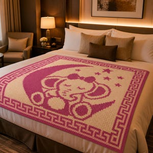May include: A pink and cream-colored crochet blanket featuring a sleeping elephant design within a crescent moon. The blanket has a Greek key border and star accents, perfect for a nursery or child's room.