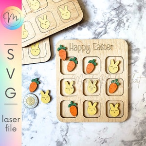 May include: A wooden game board with the words "Happy Easter" engraved on the top. The board has nine squares, each with a cutout for a small wooden piece. There are six carrot pieces and three bunny pieces, all with painted details.