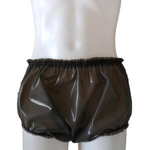 May include: Dark grey, shiny shorts made from a plastic-like material, featuring an elasticated waistband and leg openings. The shorts are gathered at the waist and legs, giving a puffy look. The material appears waterproof.