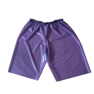 May include: A pair of shiny, purple shorts with an elastic waistband. The shorts have a smooth, reflective surface and a loose, comfortable fit. The garment is made of a material that appears to be waterproof.