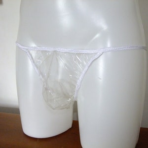 May include: A clear plastic underwear garment with white elastic trim. The garment is on a white mannequin.