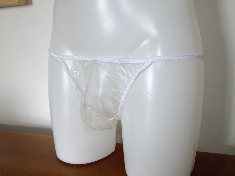 May include: A clear plastic underwear garment with white elastic trim. The garment is on a white mannequin.