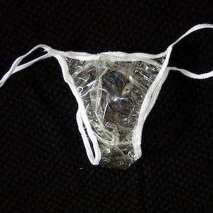May include: A clear plastic disposable underwear with white elastic trim. The underwear is designed for use in a medical or beauty setting.