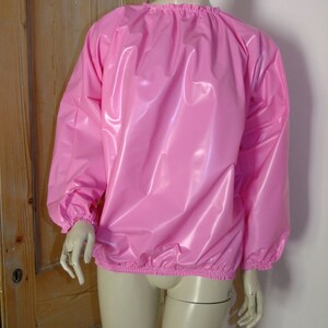 May include: A pink, shiny, long-sleeved shirt with elastic cuffs and a gathered neckline.