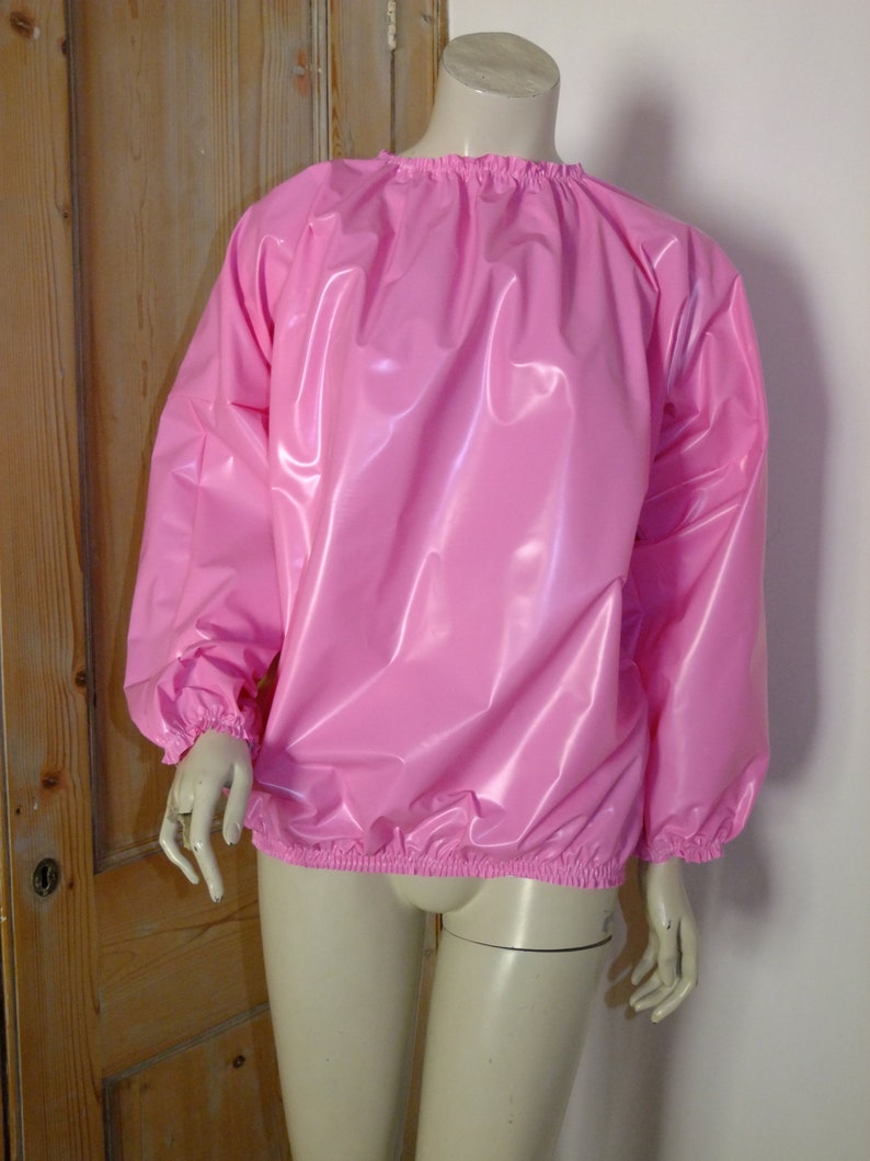 May include: A pink, shiny, long-sleeved shirt with elastic cuffs and a gathered neckline.