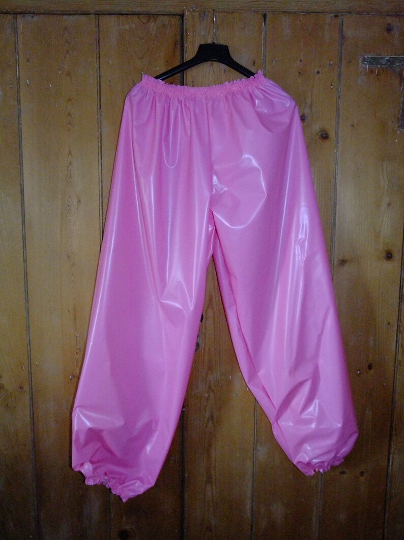 May include: Pink shiny pants with elastic waistband and cuffs. The pants are made of a smooth, silky material.