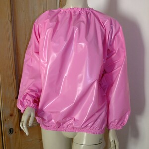 May include: A pink, shiny, long-sleeved shirt with elastic cuffs and a gathered neckline.