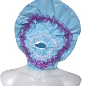 May include: A light blue shower cap with a ruffled design. The cap has purple and white lace trim around the opening and edges. The cap is made of a shiny, waterproof material.