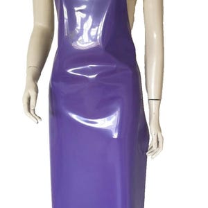 Può includere: Un grembiule viola lucido con design a collo halter. Il grembiule è realizzato in un materiale liscio e impermeabile ed è esposto su un manichino. Il grembiule è di colore pieno e ha un design semplice e funzionale, adatto a vari usi.