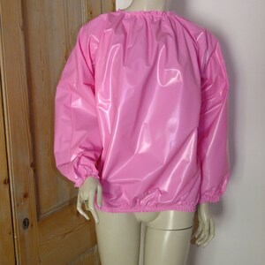 May include: A pink, shiny, long-sleeved shirt with elastic cuffs and a gathered neckline.