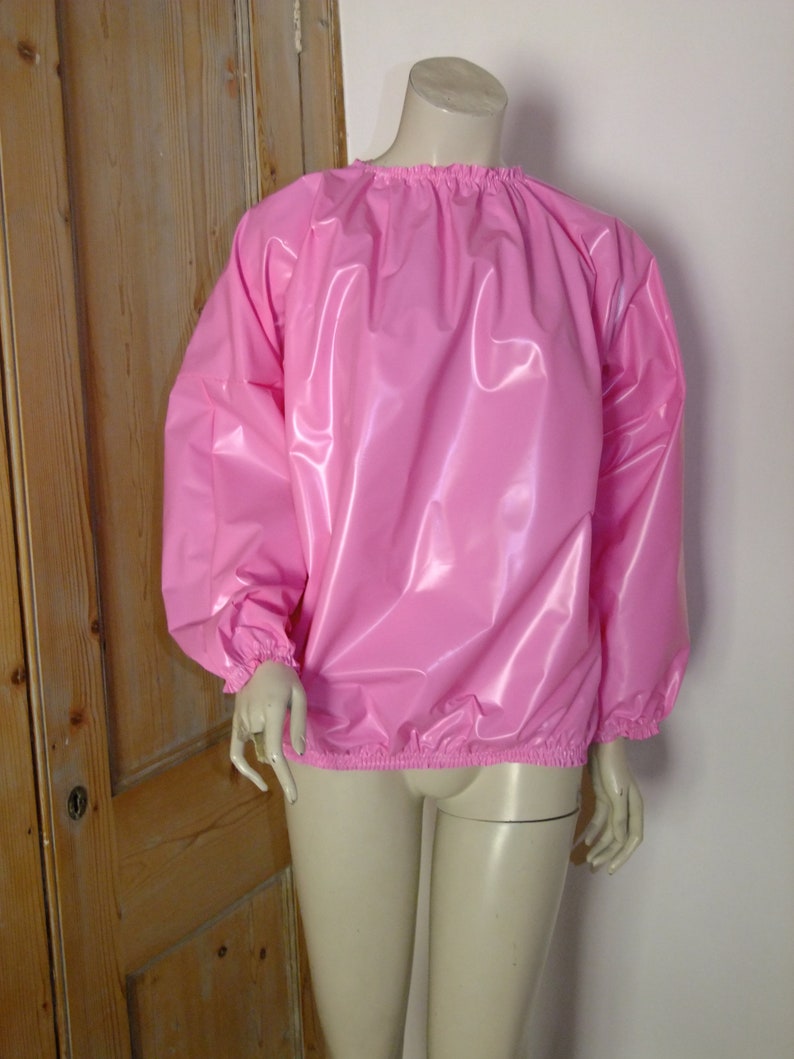 May include: A pink, shiny, long-sleeved shirt with elastic cuffs and a gathered neckline.