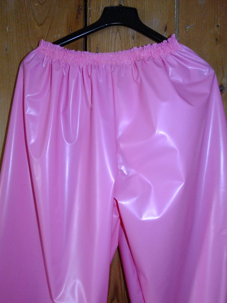May include: Pink shiny plastic pants with a gathered elastic waistband.