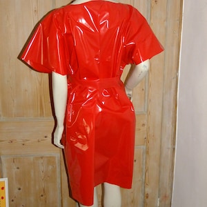 K&ouml;nnte beinhalten: Ein rotes, gl&auml;nzendes, kurz&auml;rmeliges Kleid mit einem runden Ausschnitt und einem G&uuml;rtel.