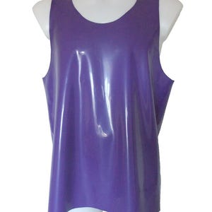Puede incluir: Un top sin mangas morado, hecho de un material brillante y liso. El top tiene un escote redondo y un diseño simple y ajustado. La prenda se exhibe en un maniquí blanco.