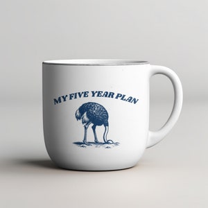 K&ouml;nnte beinhalten: Eine wei&szlig;e Keramiktasse mit einer blauen Illustration eines Strau&szlig;es, der seinen Kopf in den Sand steckt, und dem Text "MY FIVE YEAR PLAN".