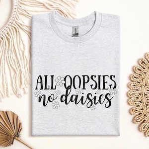 May include: Gray t-shirt with the text "All oopsies no daisies" in black lettering with small daisy graphics around the text.
