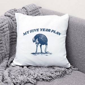 K&ouml;nnte beinhalten: Ein wei&szlig;es Kissen mit einer blauen Illustration eines Strau&szlig;es, der seinen Kopf in den Sand steckt, und dem Text "My Five Year Plan".