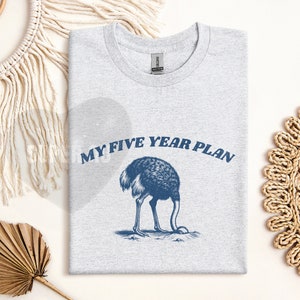 K&ouml;nnte beinhalten: Ein graues T-Shirt mit einer blauen Grafik einer Strau&szlig; mit dem Kopf im Sand und dem Text "My Five Year Plan".