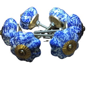 May include: A set of four ceramic drawer knobs featuring a blue and white mottled pattern. Each knob has a scalloped, pumpkin-like shape with a brass-toned metal base and a threaded bolt extending from the back for installation purposes.
