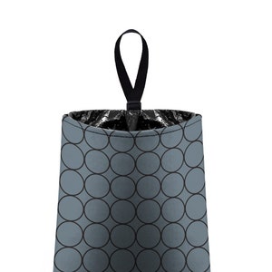 May include: A gray fabric trash can with a black handle and a circular pattern. The trash can is empty and ready to be used.