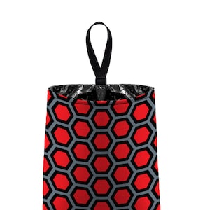 May include: Red and gray patterned trash can with a black hanging strap. The trash can is made of fabric and has a honeycomb design.