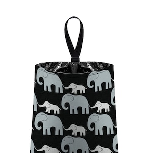 May include: Black and gray fabric trash can with a black handle. The fabric has a repeating pattern of gray elephants with their babies.