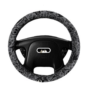 May include: A black and gray steering wheel cover with a Day of the Dead pattern. The cover features skulls, flowers, and butterflies.