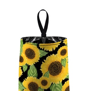 May include: A black trash can with a sunflower pattern. The trash can has a black handle and is made of fabric.