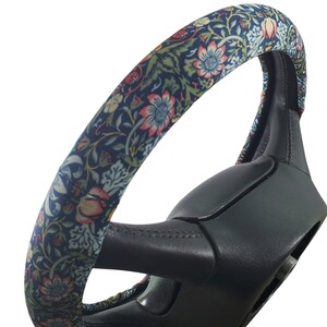 Pu&ograve; includere: Una copertura per volante con un motivo floreale nei toni del blu, rosso e verde. La copertura &egrave; avvolta attorno a un volante nero. Il design floreale presenta fiori e foglie dettagliate.